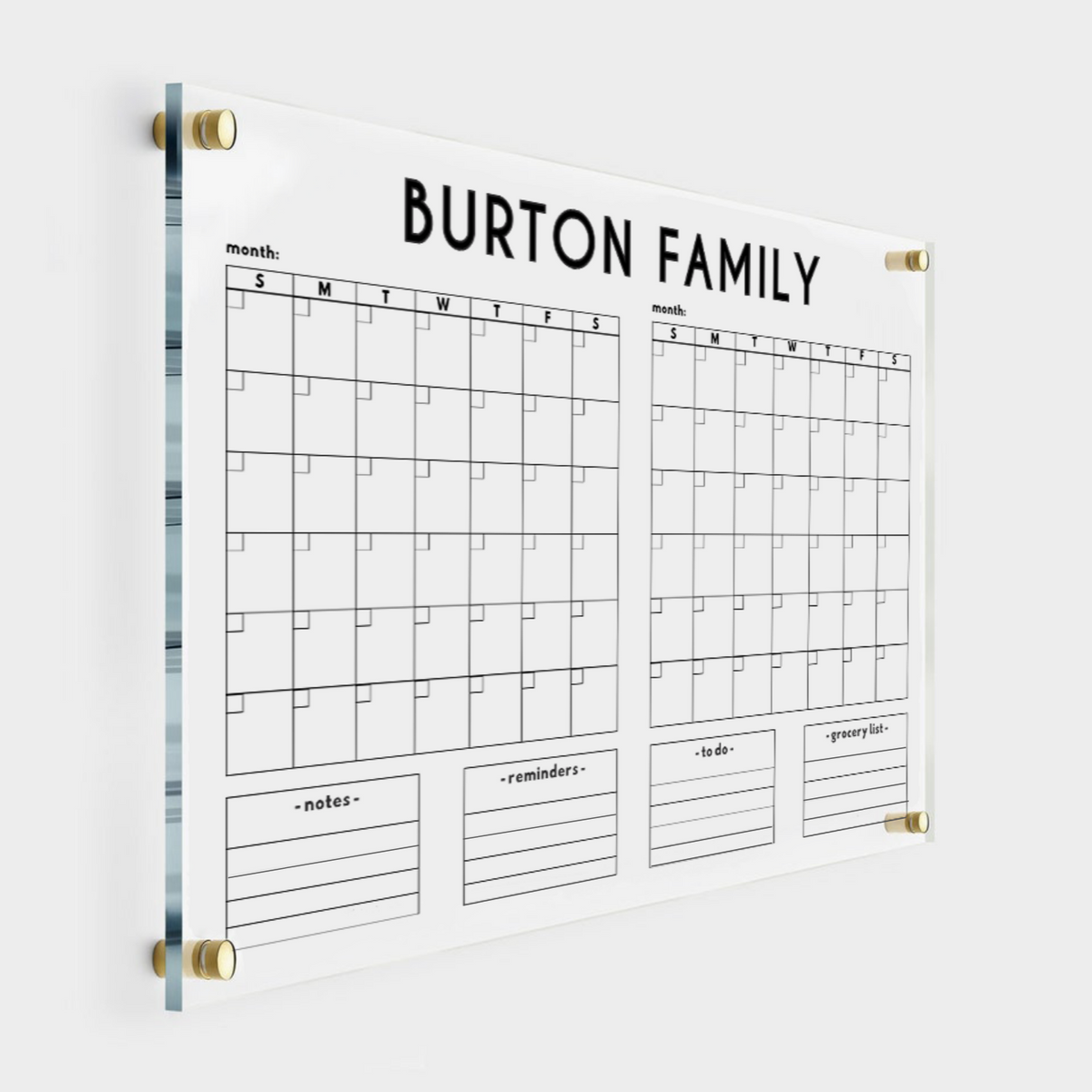 Personalized acrylic family calendar with two side-by-side monthly grids, four lined list boxes below and gold wall mounts.