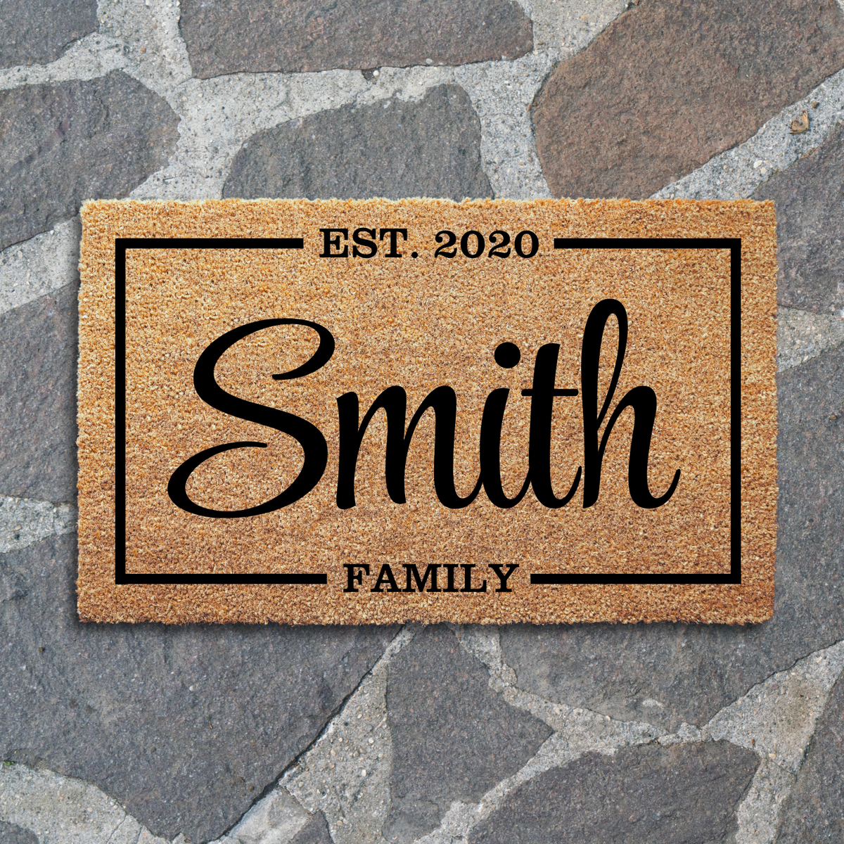 Family name special date doormat with Smith, EST. 2020 and FAMILY inside a frame, on gray flagstone paving