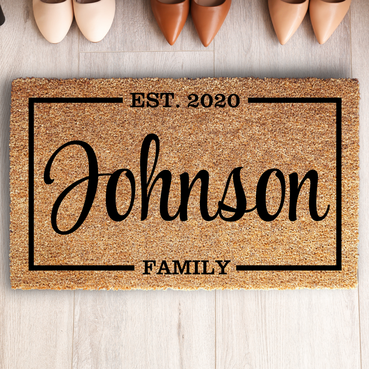 Family name special date doormat with Johnson, EST. 2020 and FAMILY inside a frame, on a light wood floor above shoes