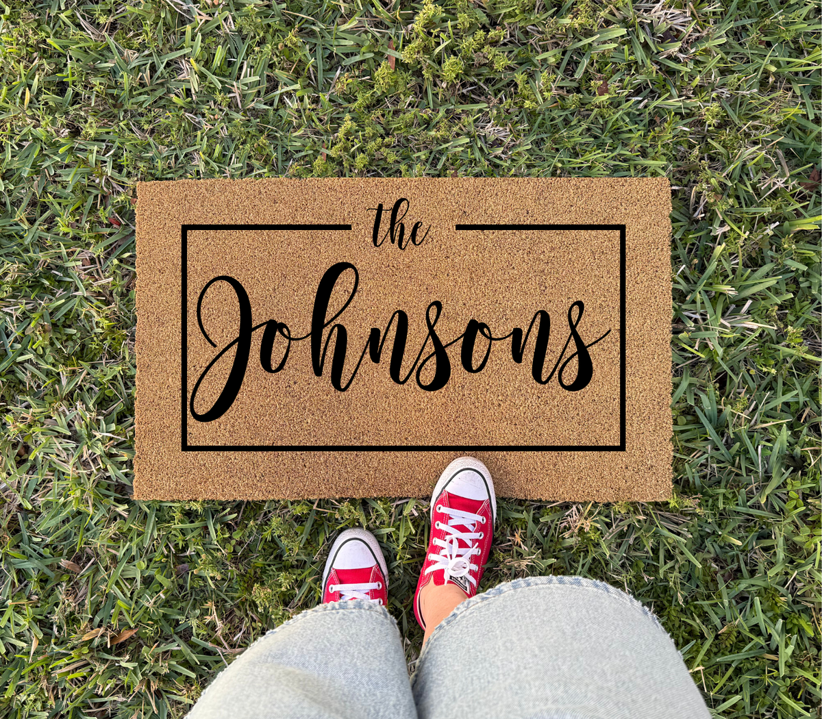 Personalized Family Name Doormat with Frame, sample name The Johnsons, on grass with red sneakers at its edge