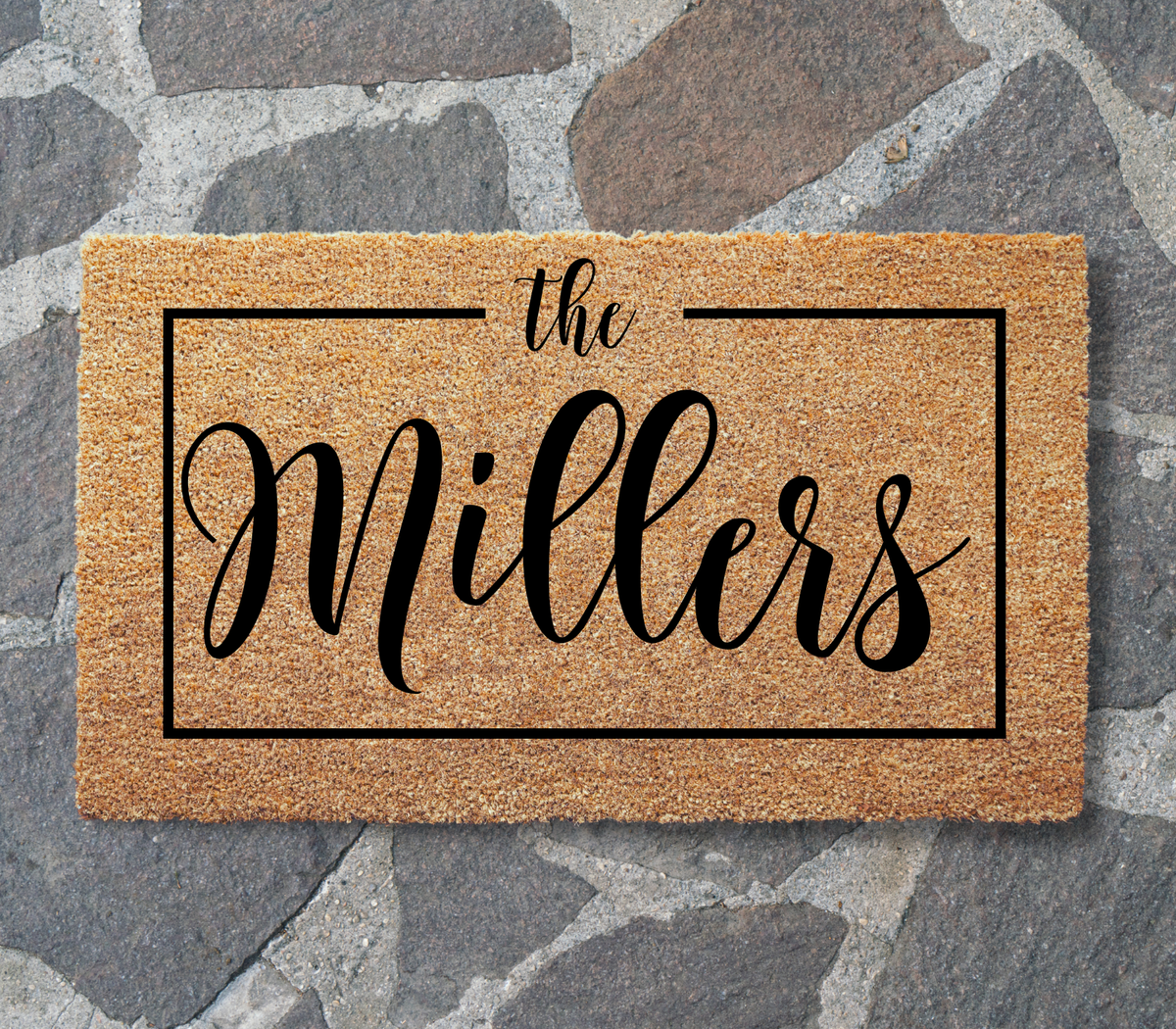 Framed family name doormat with sample name The Millers laid on gray flagstone paving