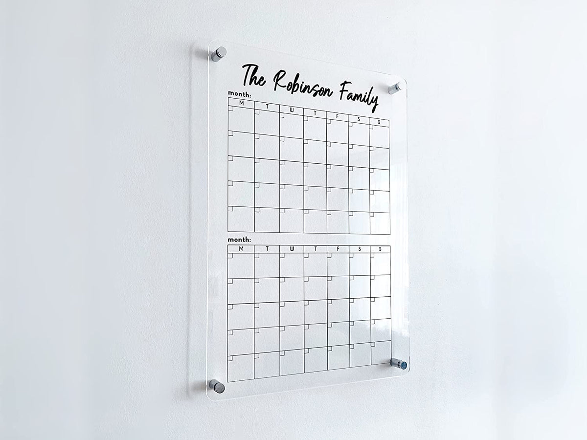 Angled detail of a personalized vertical acrylic calendar with two stacked monthly grids and raised wall mounting.
