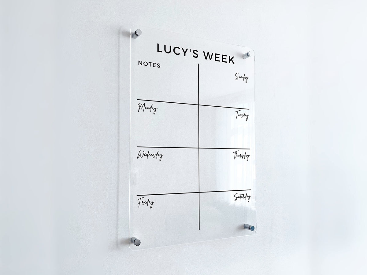 Angled view of a vertical acrylic weekly planner with seven day spaces and a Notes box below a custom heading.
