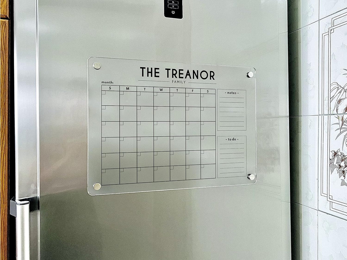 Front view of a magnetic acrylic family calendar with a monthly grid and two customizable side headings on a refrigerator.