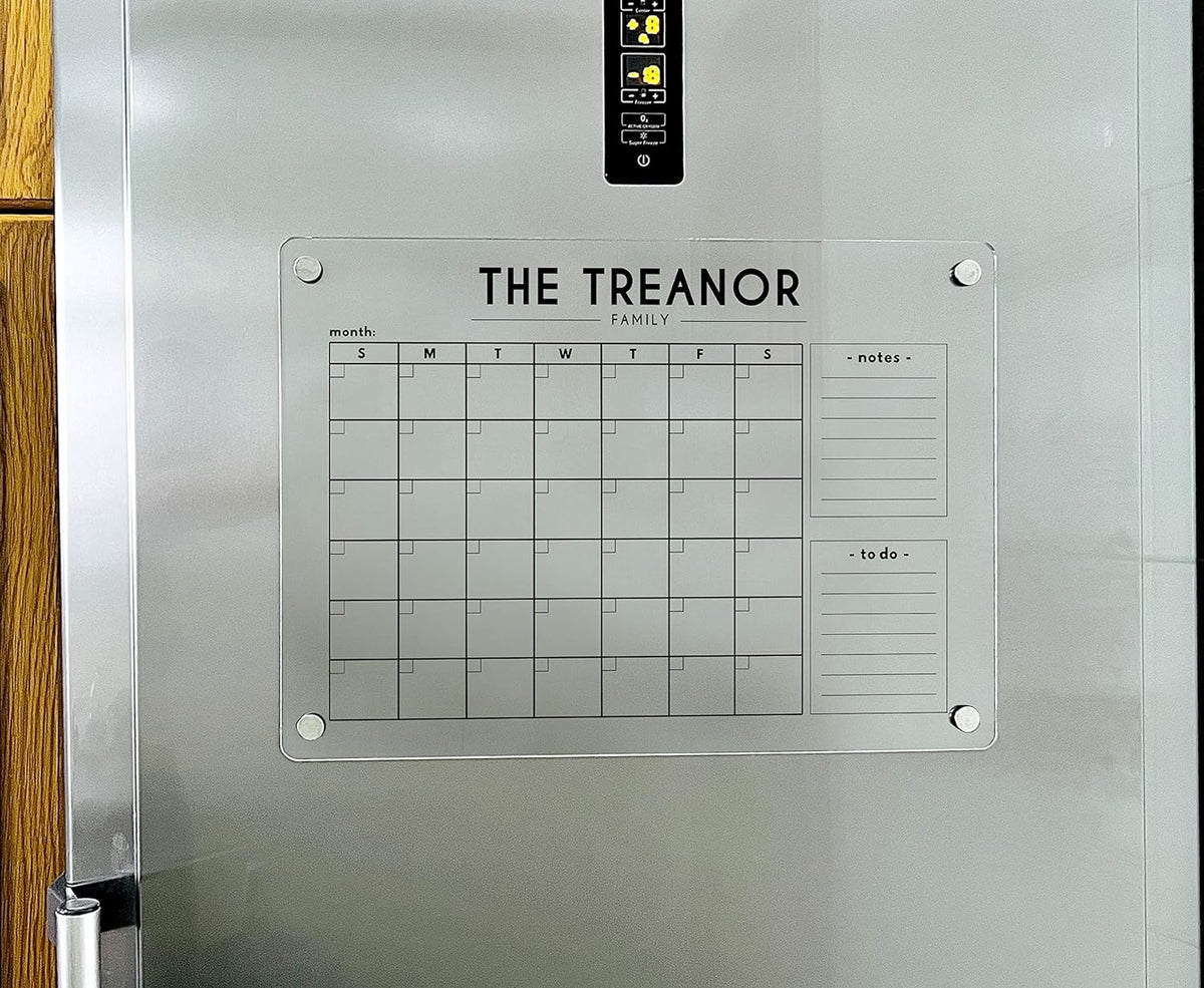 Close view of a magnetic acrylic monthly calendar with two lined side sections attached to a refrigerator.