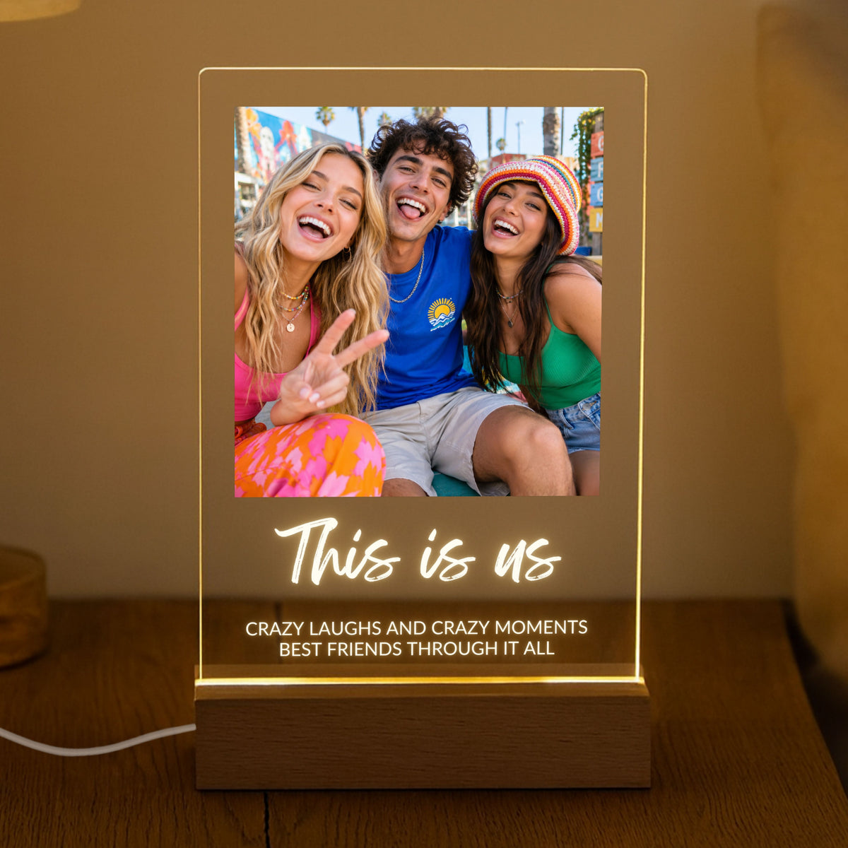 Photo Collage Plaque - Brush Script glowing on a wooden LED stand in a dark room with the sample text This is us