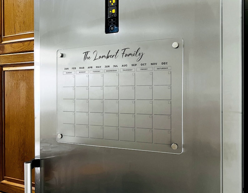 Magnetic acrylic fridge board with a monthly grid with a family name at the top.