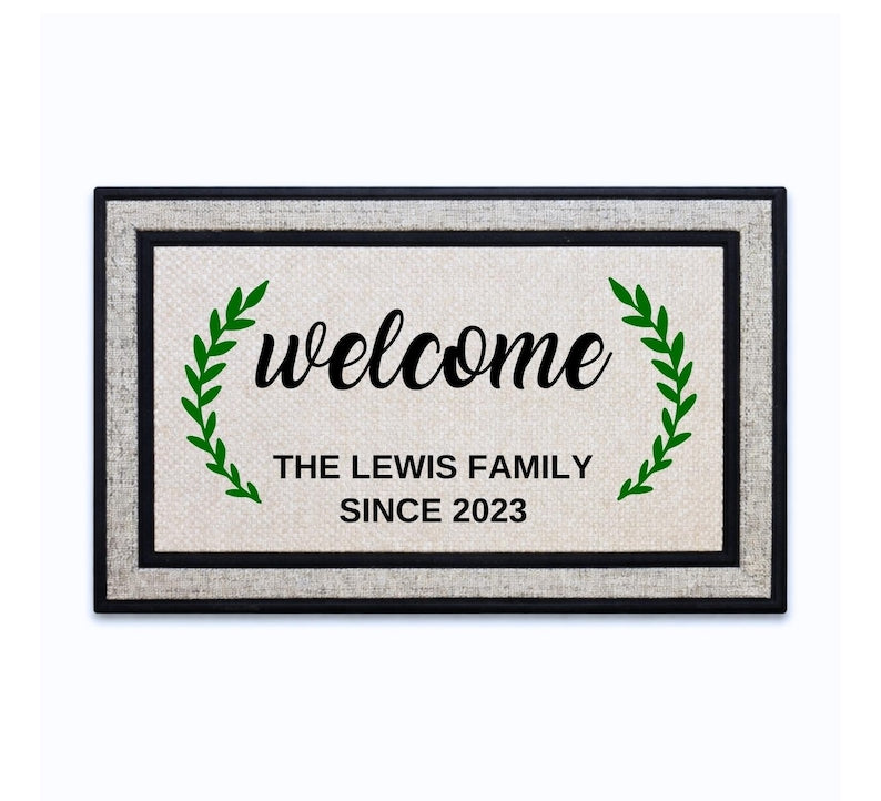 18 x 30 inch polyester doormat featuring a script welcome between green leaf branches, with family name and year.