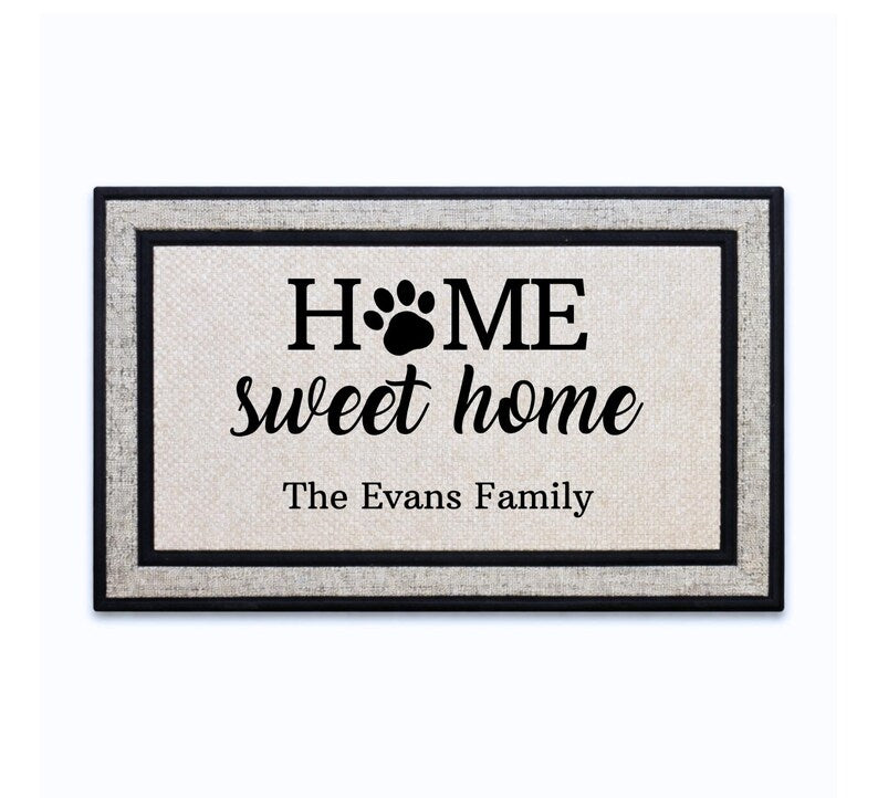 18 x 30 inch polyester doormat featuring HOME sweet home lettering with a paw print and family name.