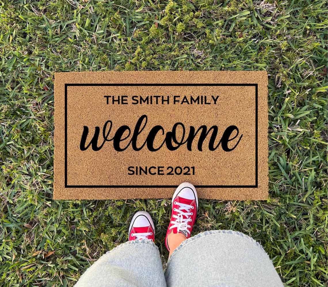 Welcome Customized Doormat on grass with sample text THE SMITH FAMILY, SINCE 2021, red sneakers at its edge