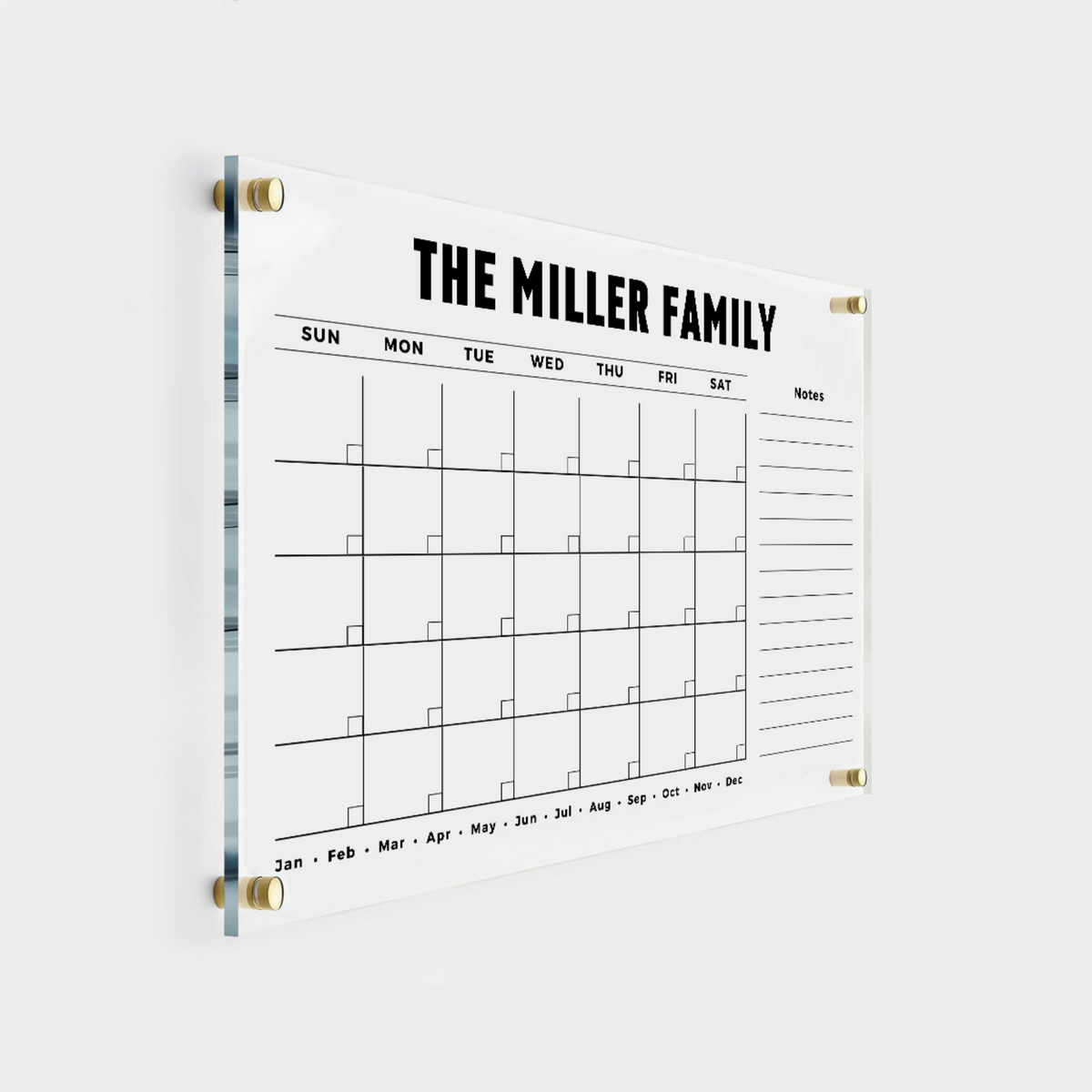 Personalized acrylic monthly calendar with a bold custom family heading, a lined right-hand notes column and gold wall mounts.